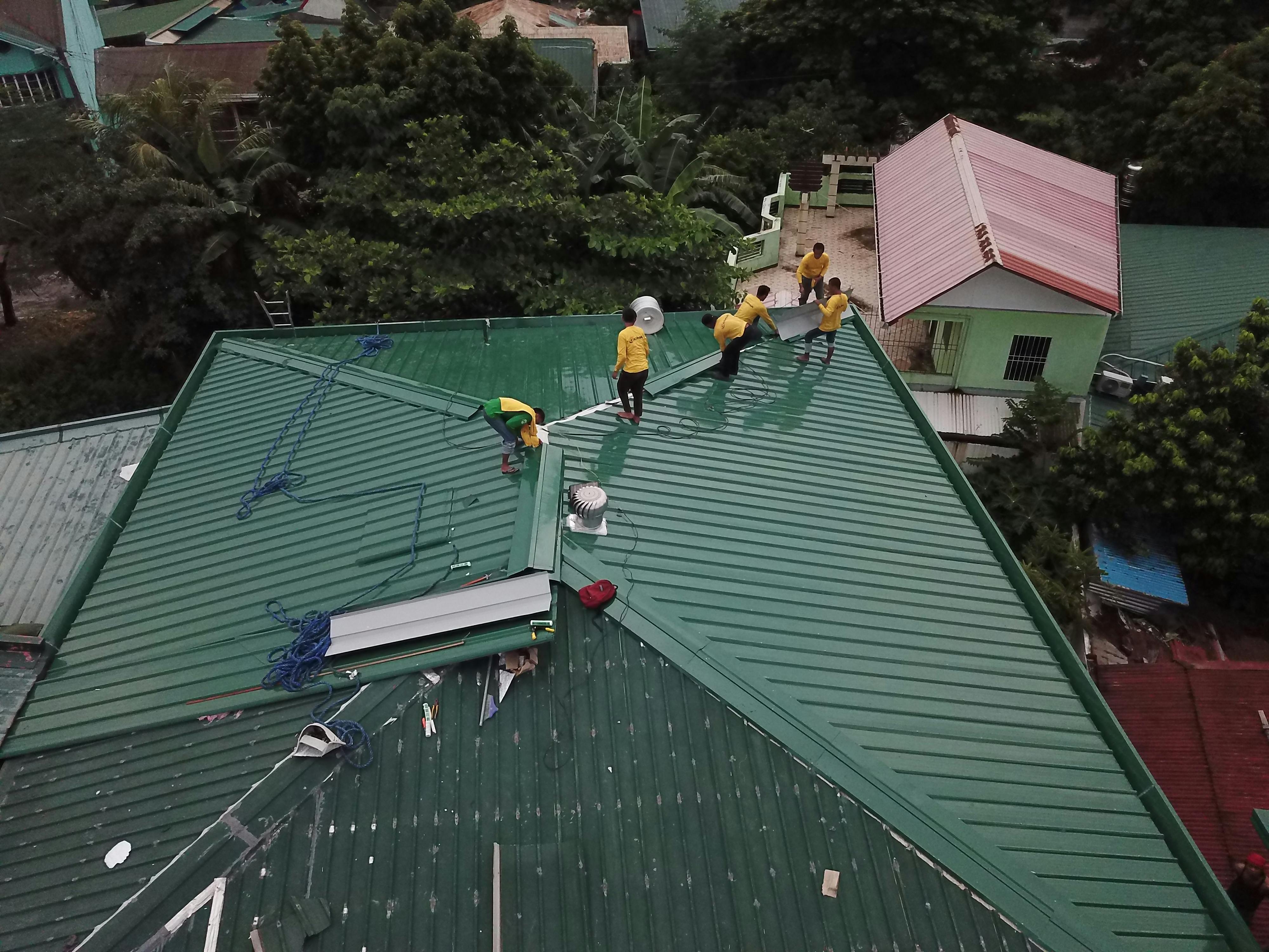 Roofer repairing shingles near the ridge of a residential roof